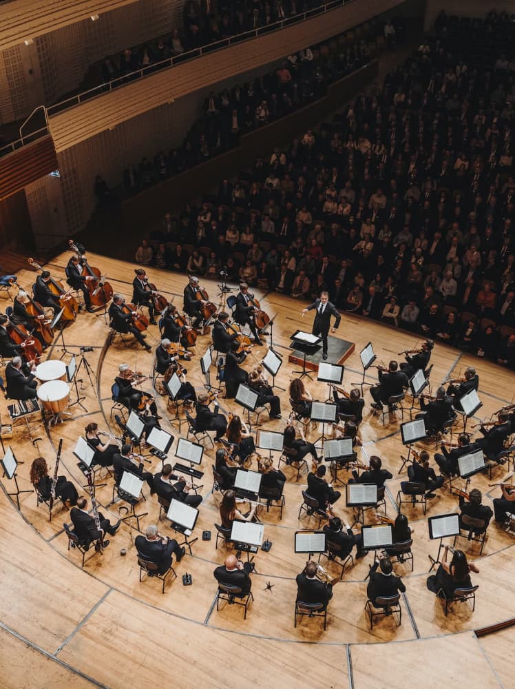 &why: Concert hall view of the KKL Luzern stage, featuring an orchestra performing in front of a full audience.