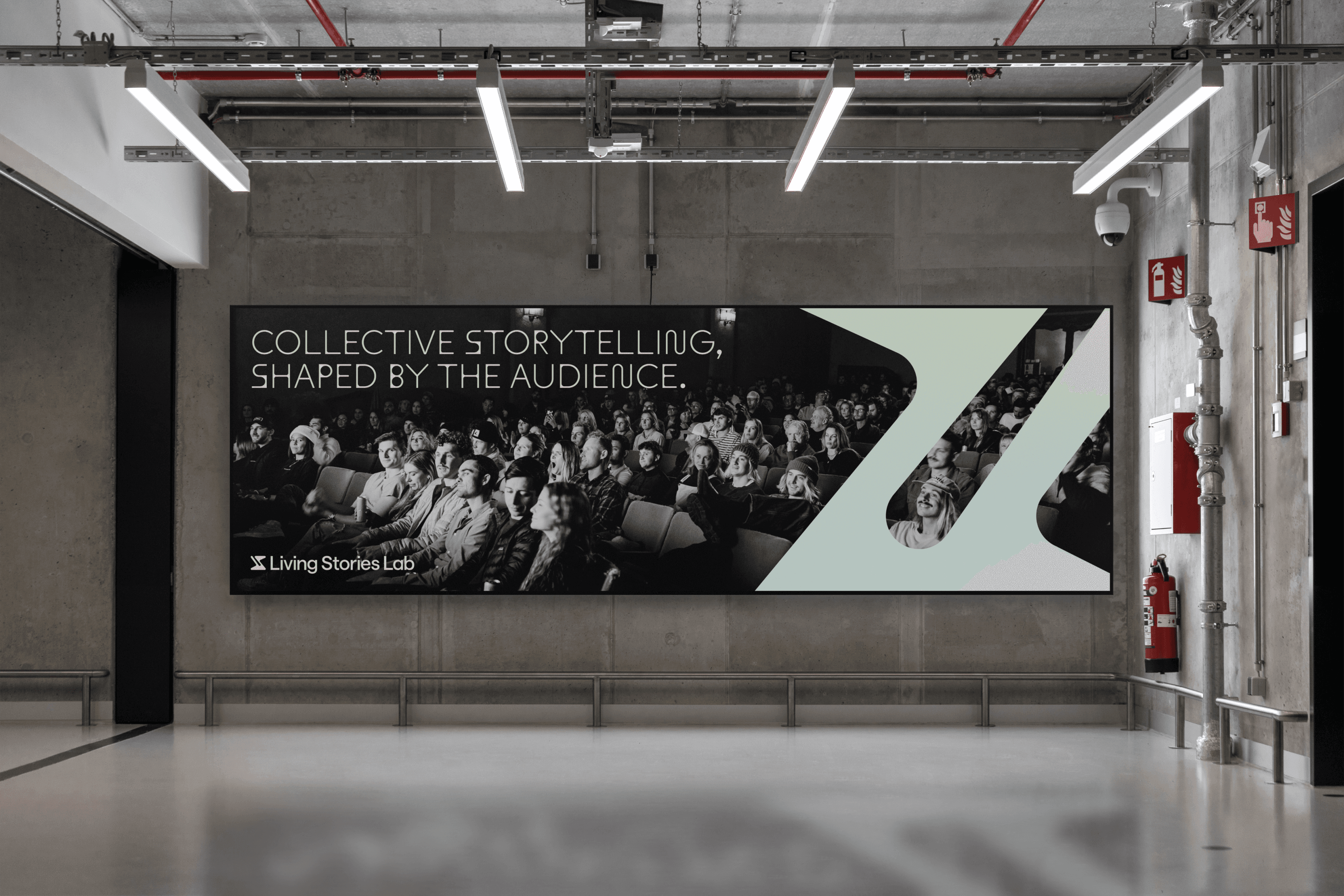 A modern hallway featuring a large digital poster on the wall. The poster has an audience sitting in a theater and the text "Collective storytelling, shaped by the audience." Minimalist design with industrial elements like concrete walls and exposed pipes.