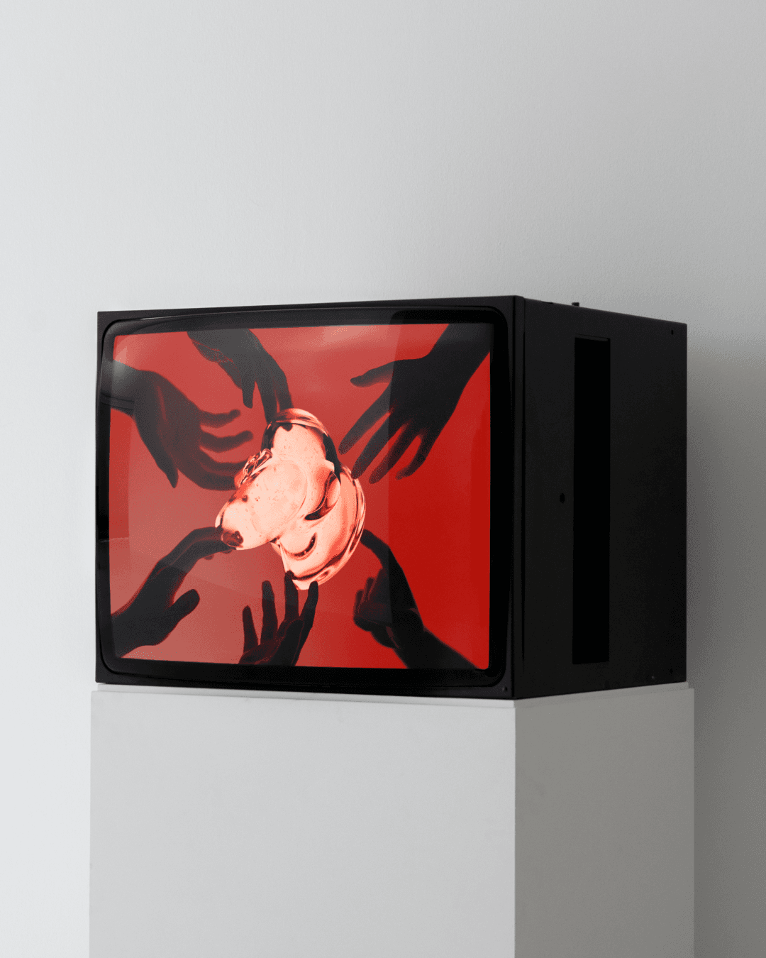 A black television on a white pedestal displays a red screen with several silhouetted hands reaching towards a central object, resembling a flower, against a glowing red background.