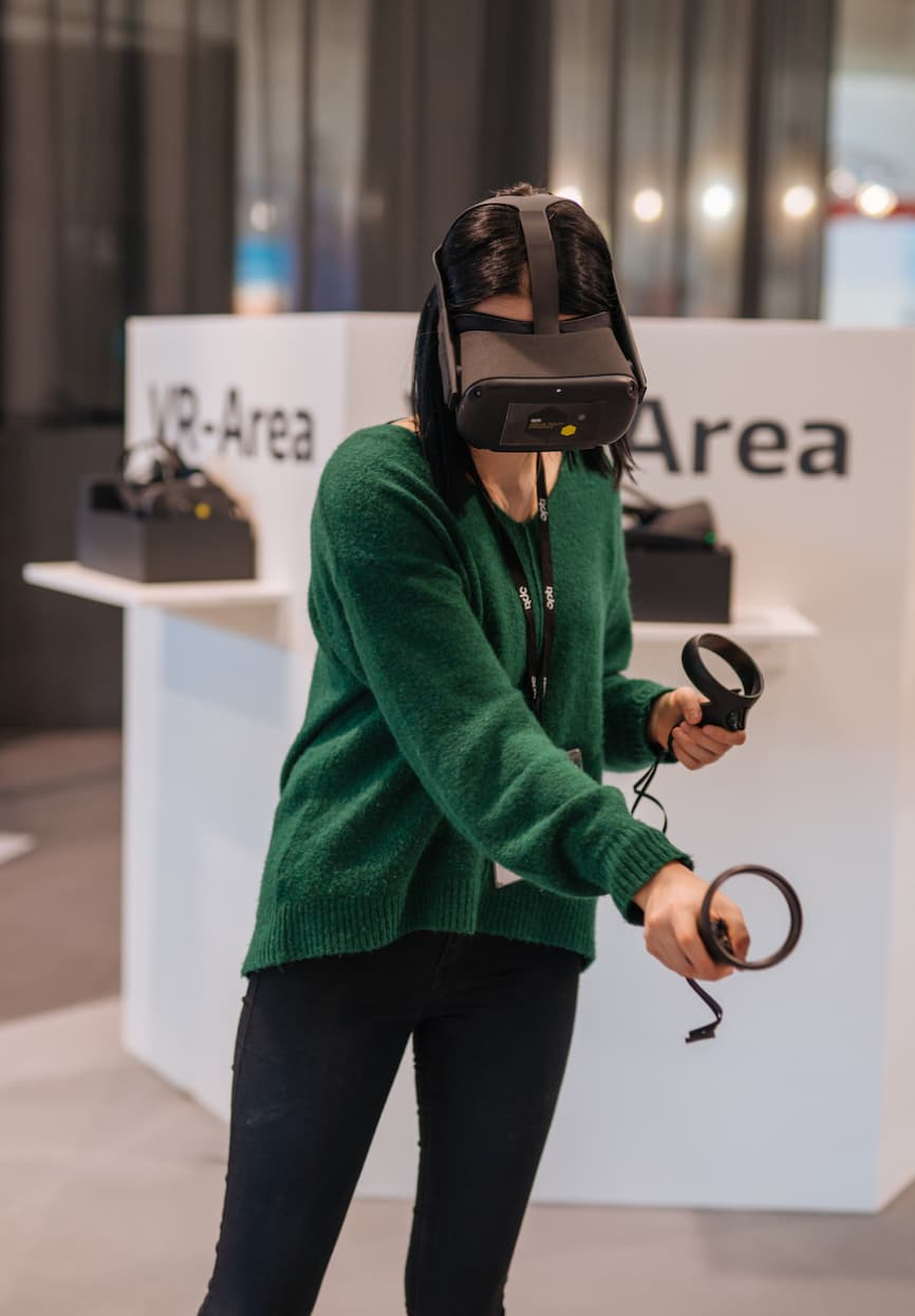 &why: opti VR - Person, die ein VR-Headset und die Steuergeräte trägt